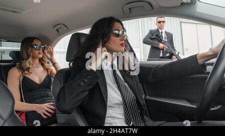 Professionelle bewaffnete Team von weiblichen und männlichen Bodyguards schützen Prominenten Person in der Auto-Limousine. Sicherheitsschutz für Bodyguard und VIP-Personen. Bekennen Stockfoto