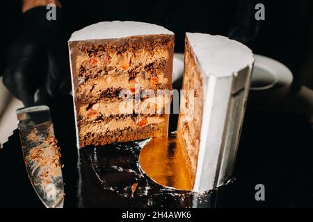 Tolle Kuchen. Geschnittener Schokoladen-Hochzeitstorte mit erstaunlicher Füllung auf schwarzem Hintergrund.großer Kuchen in weißer Schokolade. Stockfoto