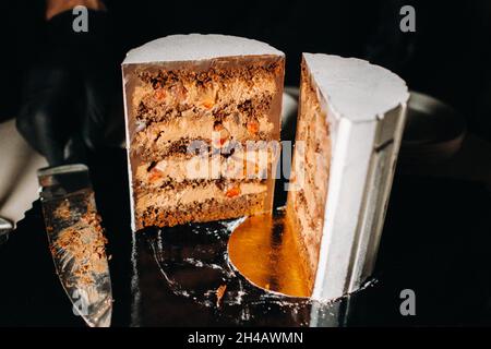 Tolle Kuchen. Geschnittener Schokoladen-Hochzeitstorte mit erstaunlicher Füllung auf schwarzem Hintergrund.großer Kuchen in weißer Schokolade. Stockfoto