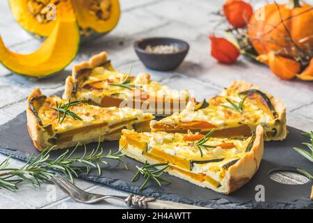 Stücke von Kürbisherb mit Rosmarin auf einem Schieferteller auf grauem Hintergrund Stockfoto