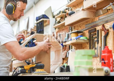 Zimmermann, der in einer Werkstatt Möbel macht der Mann stellt Holzprodukte von Hand her Stockfoto