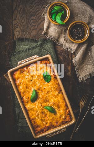 Pasta- und Käsebacken mit Tomatensauce und Basilikum auf Holzhintergrund, Draufsicht Stockfoto