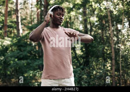 Männlicher Läufer, amerikanischer Mann, der den Fitnessfortschritt auf seiner Smartwatch überprüft, schwarzer Mann, der die Fitness-App nutzt, um die Trainingsergebnisse beim Gehen im Wald zu verfolgen Stockfoto