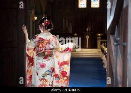 Eine Frau, die die Furisode in einer Kapelle ausbreitet Stockfoto