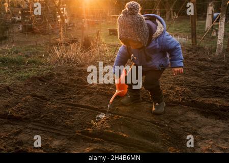 Kleinkind Junge Gießen frisch gepflanzte Pflanzen mit orange Gießen Stockfoto