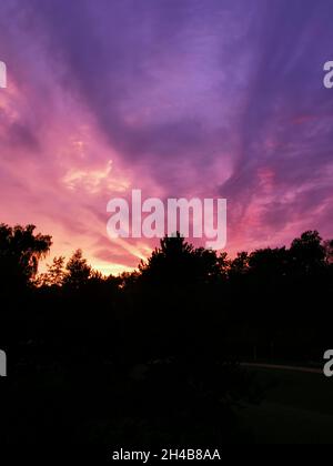 Lila Wolken und Sonnenuntergang hinter einem Berg. Stockfoto