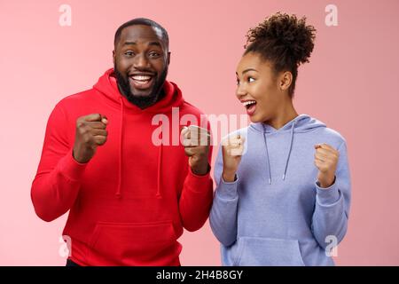 Freudig erfreut feiert afroamerikanische Frau Mann zusammen glücklich triumphierende klammernde Fäuste jubeln für Lieblings-Team beobachten Spiel Stockfoto