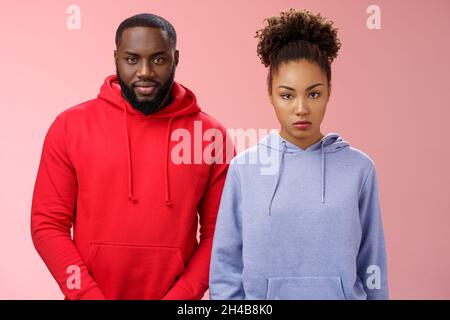 Zwei nette afroamerikanische Geschwister stehen zusammen rosa Hintergrund eingeladen Familie Abendessen begrüßen neue Mutter Freund, Schwester schauen unzufrieden ernst Stockfoto