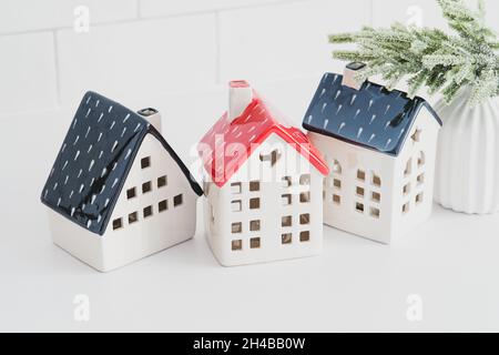 Skandinavischer Stil Weihnachten Heimdeko-Set. Dorf von keramischen Häusern und Tannenzweig auf weißem Tisch. Stockfoto