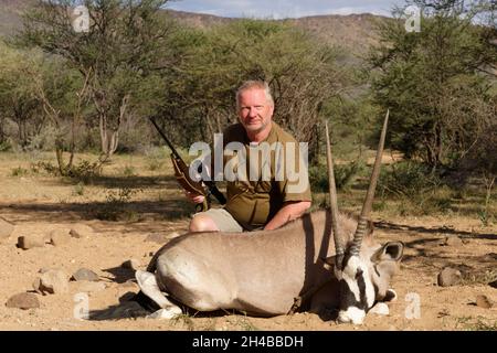 Farm Ozondjisse: Jäger mit Oryx-Antilope (Oryx gazella), Omaruru District, Erongo Region, Namibia Stockfoto