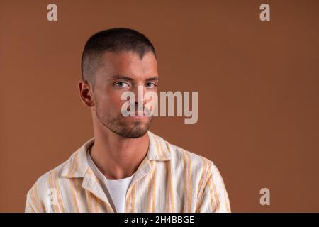 Studioportrait eines jungen Mannes auf braunem Hintergrund Stockfoto