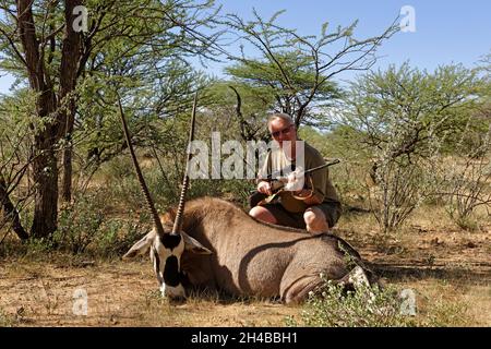 Farm Ozondjisse: Jäger mit Oryx-Antilope (Oryx gazella), Omaruru District, Erongo Region, Namibia Stockfoto