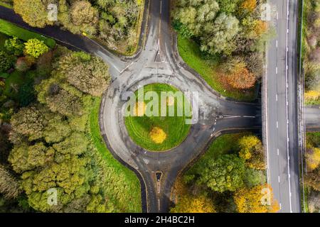 Luftdrohnenansicht eines kleinen Verkehrskreisel, umgeben von bunten Bäumen und Herbstfarben Stockfoto