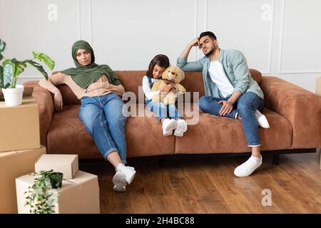 Traurige verstörte Familie aus dem Nahen Osten fühlt sich müde und lässt ihr Haus auf der Couch in der Nähe von Kartons mit persönlichen Sachen sitzen. Lange harte Verlegung d Stockfoto