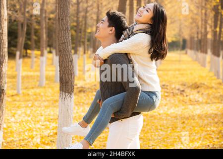 Junge Liebhaber und ihr Hund spielen im Herbst im Wald Stockfoto