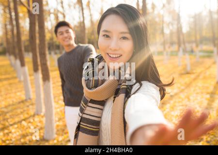 Glückliche junge Liebhaber, die im Wald spazieren gehen Stockfoto