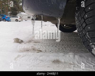 Eisscherben, die von einem hinteren Stoßfänger des Fahrzeugs herabfallen. Stockfoto