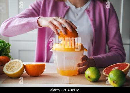 Frau, die zu Hause frischen Saft zubereitet. Gesunder Lebensstil. Morgendliche Routine Stockfoto