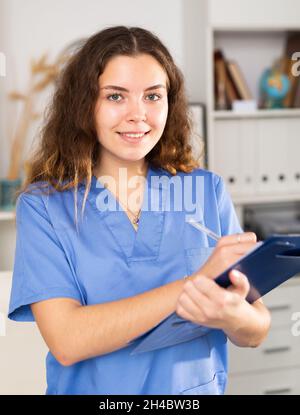Positive Ärztin in blauem Hemd im medizinischen Zentrum stehend Stockfoto
