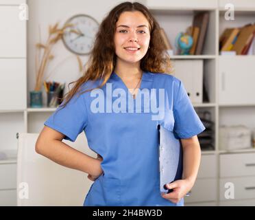 Positive Ärztin in blauem Hemd im medizinischen Zentrum stehend Stockfoto