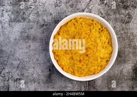 Mac und Käse, makkaroni-Pasta im amerikanischen Stil mit kitschiger Sauce und knusprigem Belag in einer weißen Backform auf dunkelgrauem Hintergrund. Draufsicht, flach l Stockfoto