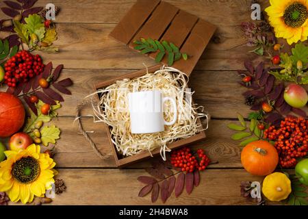 Weißer Kaffeebecher mit Sonnenblumen, Kürbissen und Herbstblättern. Leere Tasse rustikalen Mock up für Design-Promotion Stockfoto