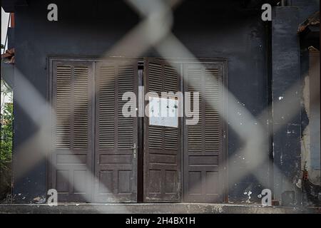 Vintage Holztüren mit Fensterläden, ein Gebäude mit dunklen Wänden. Blick durch verschwommenes Eisengeflecht. Beschriftungsplatte, Platz für Text Stockfoto