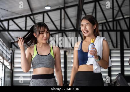 Glückliches zwei fleckiges Mädchen, das nach dem Training im Fitnessstudio miteinander redet. Stockfoto