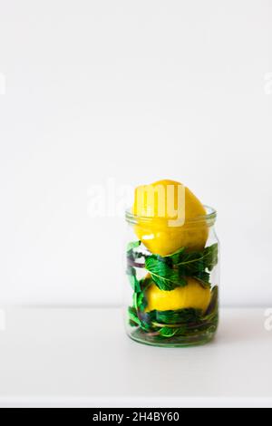 Gelbe Zitrone und grüne Minze in einem transparenten Glas auf weißem Hintergrund, Vorderansicht. Speicherplatz kopieren.