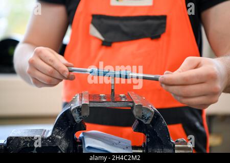 Potsdam, Deutschland. November 2021. In der Ausbildungswerkstatt der VIP Verkehrsbetrieb Potsdam GmbH bohrt ein Auszubildender aus dem 1. Jahrgang im Rahmen seiner Ausbildung einen Faden. Auf einer Presseveranstaltung vor Ort wurde die Bilanz des Ausbildungsplatzierung im Berufsausbildungsjahr 2020/21 in Brandenburg vorgestellt. Quelle: Jens Kalaene/dpa-Zentralbild/ZB/dpa/Alamy Live News Stockfoto