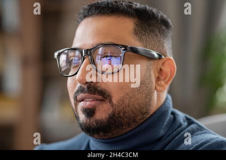 Kopf eines reifen Mannes in einer Brille, der vor dem Laptop sitzt und den Studenten während der Online-Kommunikation auf dem Bildschirm ansieht Stockfoto