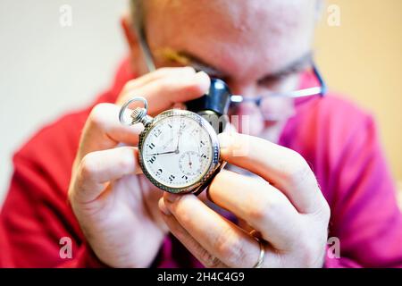 Mannheim, Deutschland. Oktober 2021. Tobias Rackstraw, Gutachter im Pfandhaus, untersucht eine Uhr mit Lupe im Pfandhaus. Wenn das Geld knapp ist, locken Pfandhäuser Kunden mit schnellem Bargeld. (To dpa 'trinkets for money - Pfandhäuser wetten auf Weihnachtsgeschäft') Kredit: Uwe Anspach/dpa/Alamy Live News Stockfoto