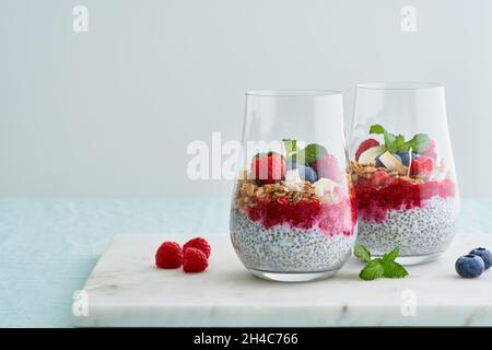 Chia-Dessert in mehreren Lagen. Heidelbeere, Himbeermarmelade, Cremejoghurt, geschälte Mandeln Stockfoto