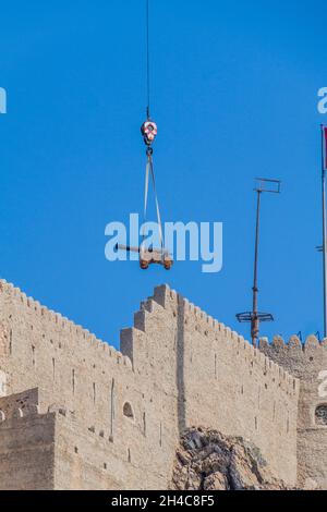 Kran transportiert eine Kanone zum Mutrah Fort in Muscat, Oman Stockfoto