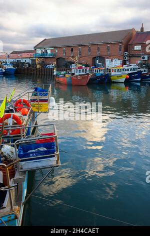Kleine Fischerboote liegen im Scarborough-Binnenhafen neben dem Anlegesteg für die Fischverarbeitung Stockfoto