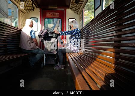 Ein älteres Paar mit Masken und Kinderwagen fährt auf der viktorianischen Straßenbahn vom Strand in die Stadt Scarborough Stockfoto
