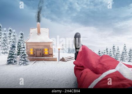 Holzhaus mit dem Weihnachtsmann auf dem Schneefeld. Frohe Weihnachten Stockfoto