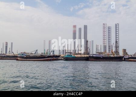 Boote, Ölabstürze und Kraniche im Hafen von Khalid in Sharjah, Vereinigte Arabische Emirate. Stockfoto