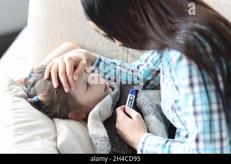 Eine fürsorgliche Mutter berührt die Stirn eines kranken Mädchens Stockfoto