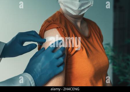 Arzt, der nach dem Covid-19-Impfverfahren Gips auf die weibliche Schulter aufsetzt, Impfkonzept Stockfoto