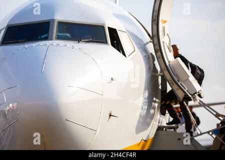 Personen, die am Flughafen in ein Flugzeug steigen. Konzentrieren Sie sich auf die Nase des Flugzeugs. Stockfoto