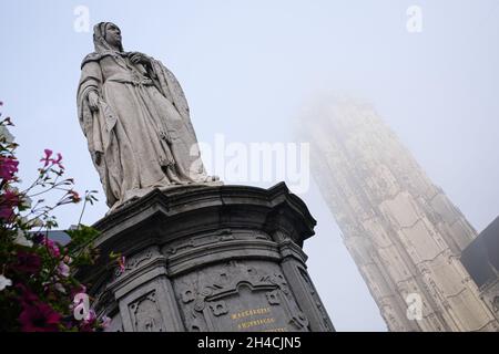 MECHELEN, BELGIEN - 16. Oktober 2021: Die Statue der Margarete von Österreich im Zentrum von Mechelen, Belgien, ragt Sint-Rumbolds im Nebel zurück Stockfoto