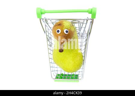 Anthropomorphe frische Birne in einem Spielzeug-Einkaufswagen isoliert auf weißem Hintergrund. Stockfoto