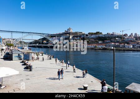 Fußgängerpromenade entlang des Douro in der Altstadt von Porto. Im Hintergrund ist die Brücke Pond Luis I zu sehen. Menschen flanieren, are not to . Stockfoto