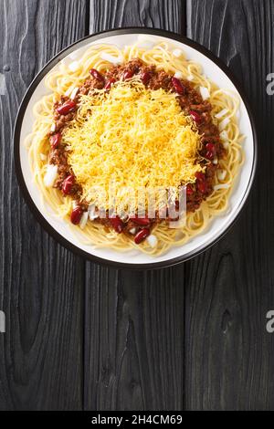 Authentic Cincinnati Chili ist ein fleischiges, reiches und einzigartig gewürztes Chili, das über heiße Spaghetti mit Käseauflagen in der Nähe auf dem Blac-Teller serviert wird Stockfoto