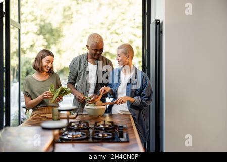 Freunde kochen Salat zusammen in der heimischen Küche Stockfoto