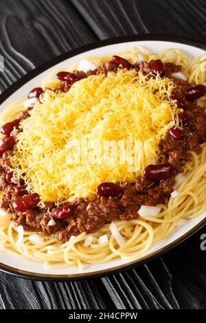 Cincinnati Chili oder Cincinnati Stil Chili ist eine mediterrane gewürzte Fleischsoße, die als Belag für Spaghetti in der Nähe auf dem Teller auf dem schwarzen Tisch verwendet wird Stockfoto