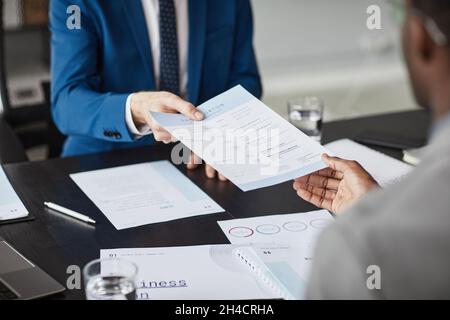 Nahaufnahme von zwei Geschäftsleuten, die während der Besprechung im Büro Dokument über den Tisch übergeben, Kopierfläche Stockfoto