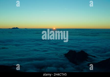 Die Sonne schleicht sich langsam am Horizont und zeigt eine so erstaunliche Landschaft. Sonnenaufgang in den Bergen. Sonnenaufgang über den Wolken. Stockfoto