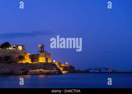 Nightscape in Malta, Belagerung Bell war Memorial und St Elmo Bridge in der Nacht am Seeufer der Sciberras Halbinsel im Mittelmeer. Stockfoto